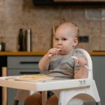 Cute baby enjoying a meal in a high chair, showcasing innocence and joy indoors.